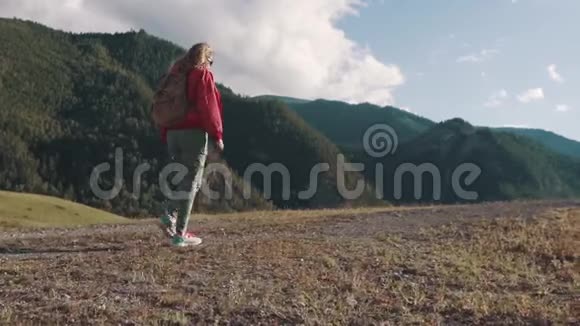旅行者爬山一位背着背包的女游客沿着山区的地形散步视频的预览图