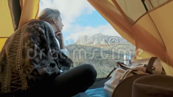 美丽的金发女郎走进帐篷露营就在大山上孤独中的自由概念视频的预览图