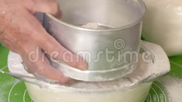 特写成熟的女人将面粉倒入一个筛子中并将其放入装有测试材料的玻璃碗中视频的预览图