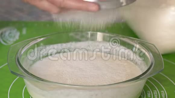 特写镜头成熟的女人用玻璃器皿中的筛子擦拭面粉并为测试提供配料视频的预览图