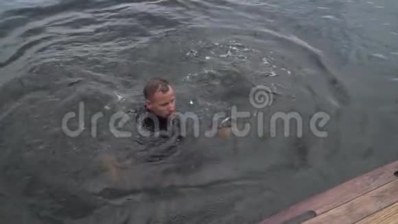 穿着潜水衣的年轻人正在河里游泳视频的预览图