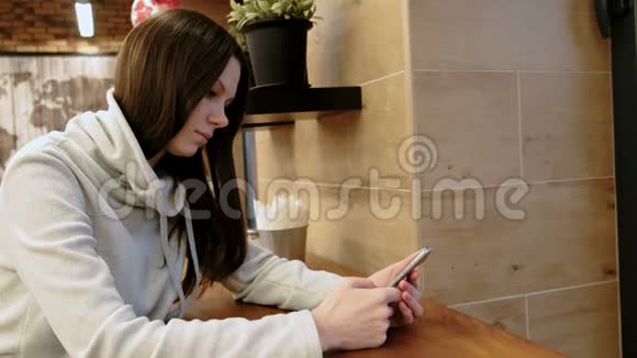 坐在咖啡馆里一位身穿亮色衬衫忧郁的年轻黑发女人在手机里读着这条信息视频的预览图