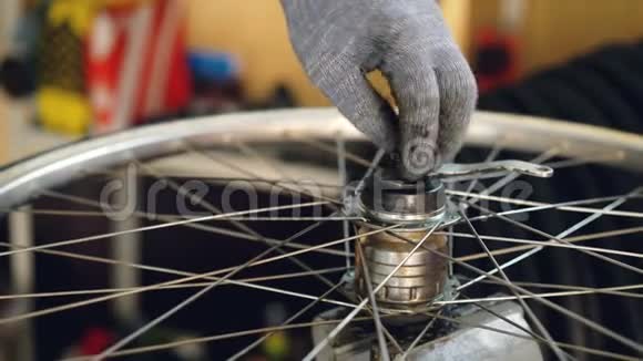 自行车车轮紧固金属螺钉的保护手套装配机构中男性手的特写镜头工作视频的预览图