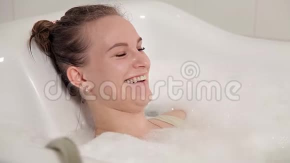 一个穿着泳衣的年轻女孩在水疗中心度过了一段时间她躺在浴室里用水疗按摩视频的预览图