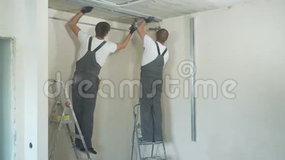 在室内施工现场使用电钻组装金属干壁型材的男性建筑工人视频的预览图