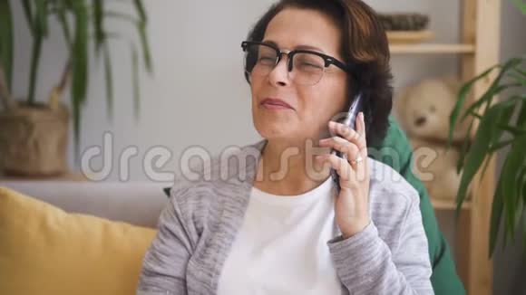 戴着棕色头发眼镜的成熟女人坐在沙发上视频的预览图