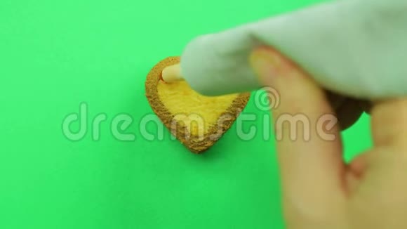 女性的手在绿色的背景上画一个心形的饼干红色的管子结霜有趣的表情符号视频的预览图