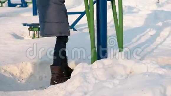 在城市的冬季公园里特写女子腿从事滑雪模拟器雪花飘来飘去视频的预览图