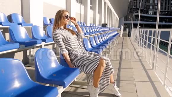 时尚的年轻女性在炎热的晴天在空场馆放松的慢镜头视频的预览图
