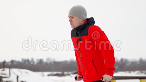 一个受过体育训练的人在冬天在露天的双杠上做俯卧撑侧视慢速运动120架视频的预览图