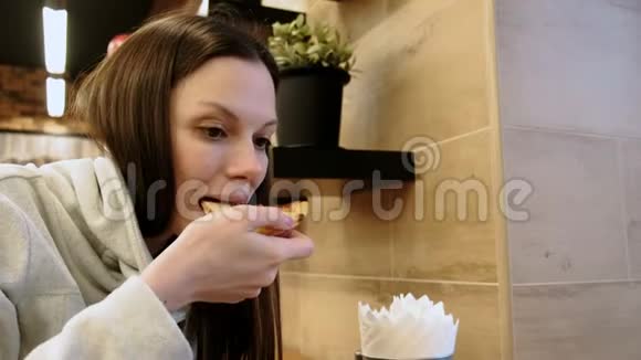 布鲁内特年轻饥饿的女人咬了一块美味的披萨咀嚼它侧视视频的预览图