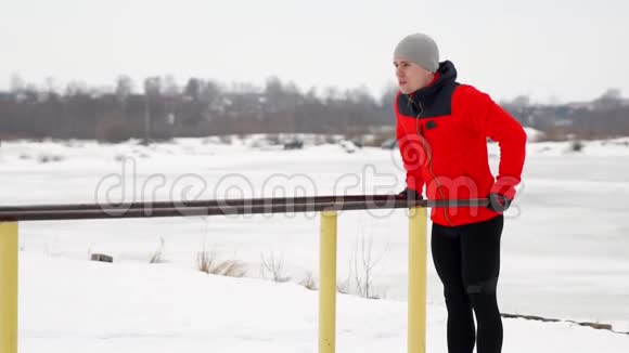 一个受过体育训练的人在冬天在露天的双杠上做俯卧撑侧视慢速运动120架视频的预览图