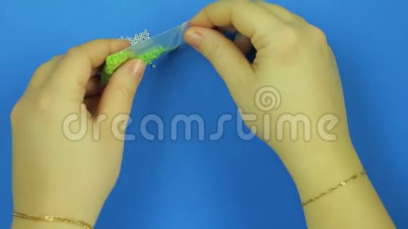 女人把绿色的珠子洒在蓝色的背景上特写镜头视频的预览图