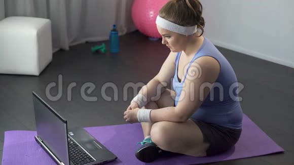 胖女孩在笔记本电脑上观看有著名训练方法的在线视频视频的预览图
