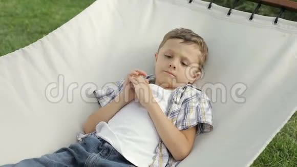 可怜的小男孩躺在吊床上视频的预览图