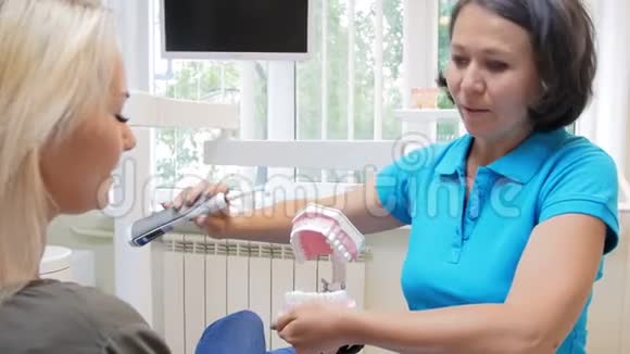 4k段牙医教育女性病人用电刷清洁牙齿视频的预览图