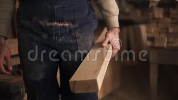 一个年轻的木匠用粗糙的手缓慢移动的画面一个男人穿着一件脏兮兮的穿着一件带着木粉的蓝色工作服视频的预览图