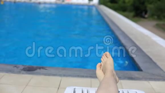 女人的腿在游泳池的背景上蓝色的水在露天旅游健康生活方式视频的预览图