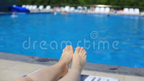 女人的腿在游泳池的背景上蓝色的水在露天旅游健康生活方式视频的预览图