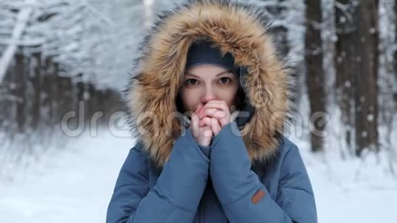 女人在寒冷中温暖她赤裸的双手在冬天的森林里呼吸视频的预览图