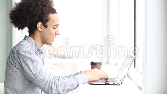 侧面看年轻人用笔记本电脑工作喝咖啡视频的预览图