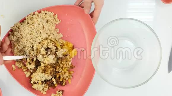 女人把坚果和干果混合在玻璃碗里烹饪健康的食物顶视图4K视频的预览图