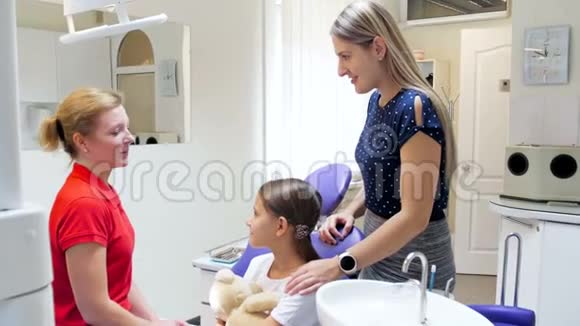 在牙科诊所年轻母亲和十几岁的女孩与牙医交谈的4K镜头视频的预览图