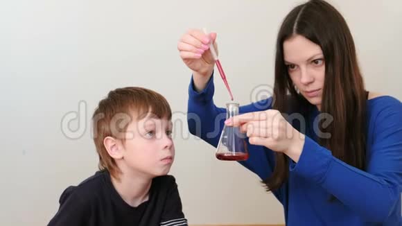 母亲和儿子用吸管烧瓶和红色液体做化学体验视频的预览图
