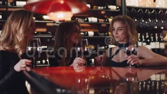 三个漂亮的女朋友坐在酒吧旁举起酒杯敬酒欢呼喝红酒视频的预览图