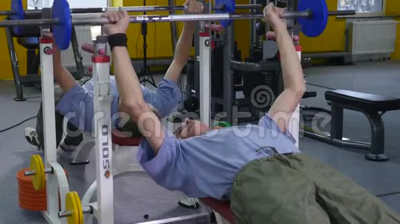 肌肉发达的老人在健身房里用长凳压着锻炼身体强壮健康视频的预览图