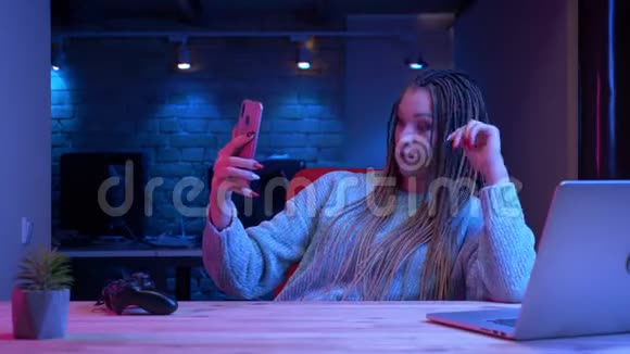 年轻有魅力的女性博客写手用霓虹灯在手机上直播的特写镜头视频的预览图