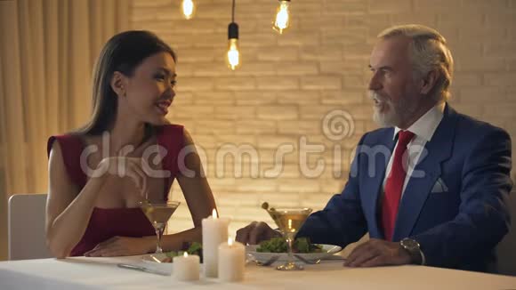 在餐馆吃饭的时候一个漂亮的女人在和年长的百万富翁调情视频的预览图