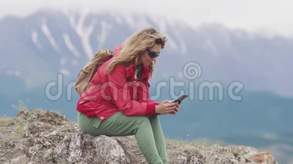 旅行者在山上放松时使用智能手机女游客拿着手机视频的预览图
