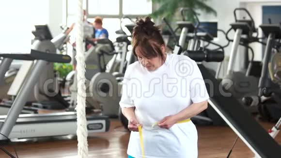 在健身房测量腰部的高级女人视频的预览图