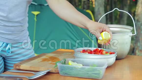 一个年轻的女人在野餐时用沙拉把柠檬汁挤到碗里视频的预览图