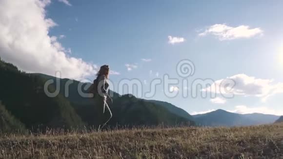 一个背着背包的旅行者沿着山顶在群山的背景下行走女游客视频的预览图