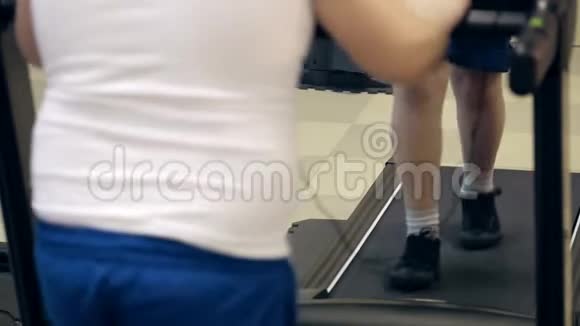 一个体重过大的小男孩的腿和厚厚的身体他在室内的健身房里训练跑步机视频的预览图