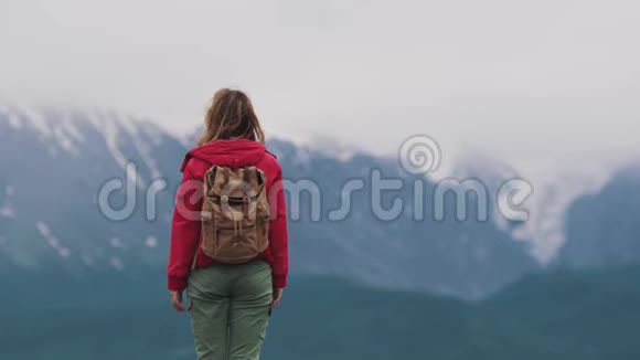 一个带背包的女孩在山里旅行的肖像视频的预览图