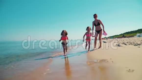 两个可爱的女孩正在海边的沙滩上奔跑视频的预览图