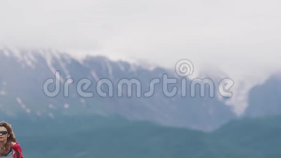 旅游女孩在山峰的背景下走向镜头一个在山野里的旅行者视频的预览图