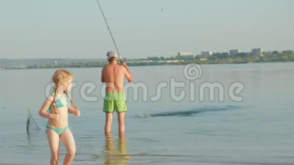 爱英俊的父亲和可爱的女儿他们拿着钓竿站在水里一起钓鱼视频的预览图