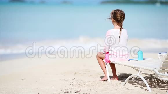 在日光浴中享受热带海滩度假的小女孩望着大海视频的预览图