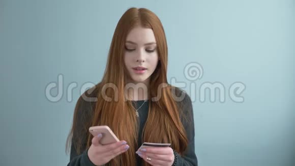年轻漂亮的红发女孩在网上购物网上银行使用智能手机购物并提供信用视频的预览图