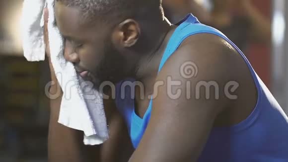 非裔美国人在健身房用毛巾擦脸训练后筋疲力尽视频的预览图