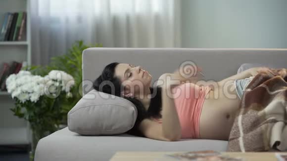 美丽的孕妇甜美地睡在沙发上抱着肚子抱着婴儿视频的预览图