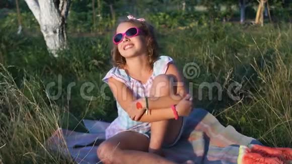 在大自然中野餐一个十几岁的女孩坐在村里的草地上晒太阳她戴着粉红色的太阳镜上面有绷带视频的预览图