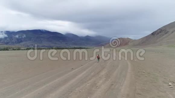 一个孤独的旅行者沿着山上的一个石谷散步带背包的女游客视频的预览图