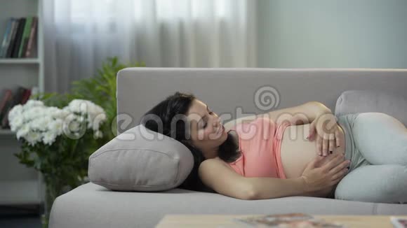 年轻的未来母亲抚摸她的肚子与即将出生的新生儿交流视频的预览图