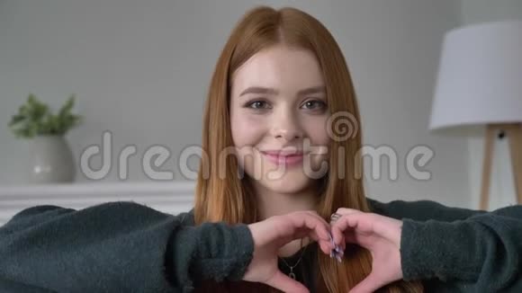 年轻的红发女孩博客作者肖像看着相机微笑显示出心爱家的安慰视频的预览图