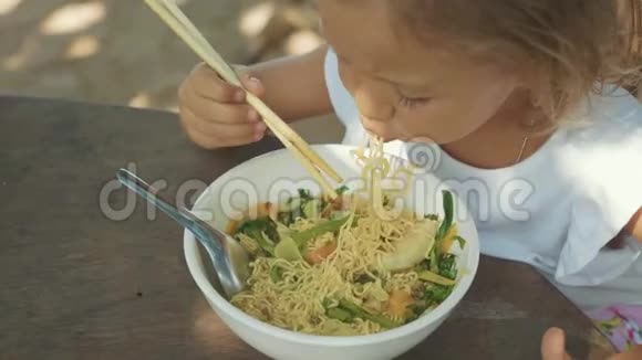 女孩在露天海滩咖啡馆用筷子吃面条汤视频的预览图